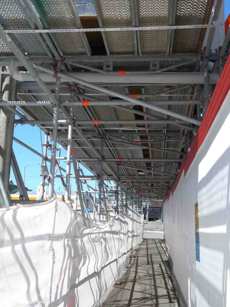 Service pipes accommodated with scaffolding beneath overhead contruction site office