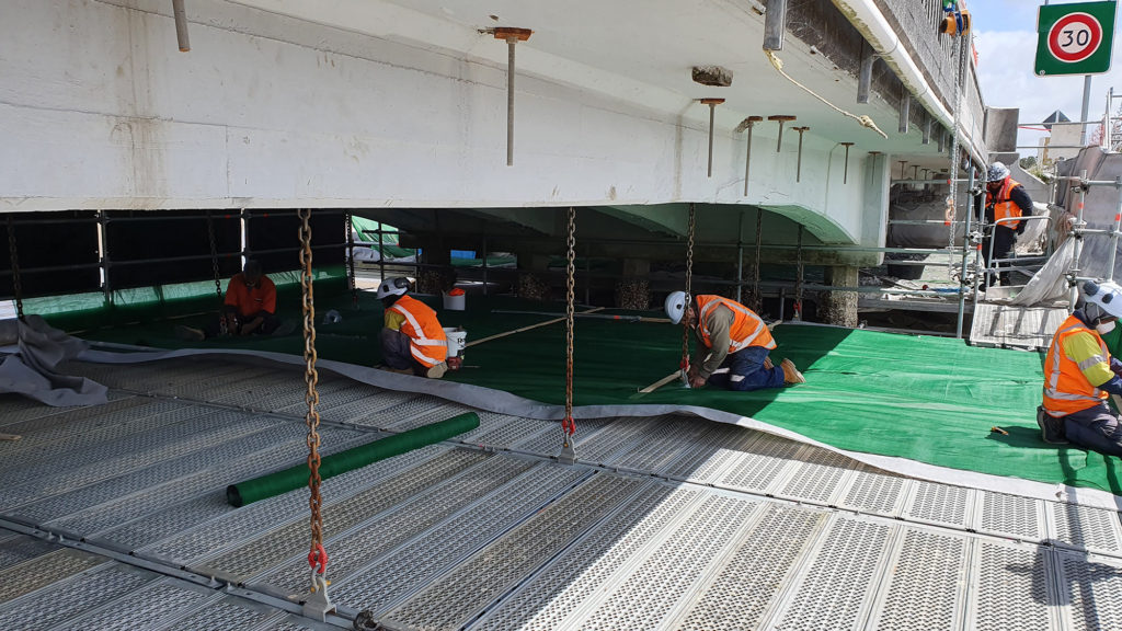 Contractors on secure working platform on underside of bridge